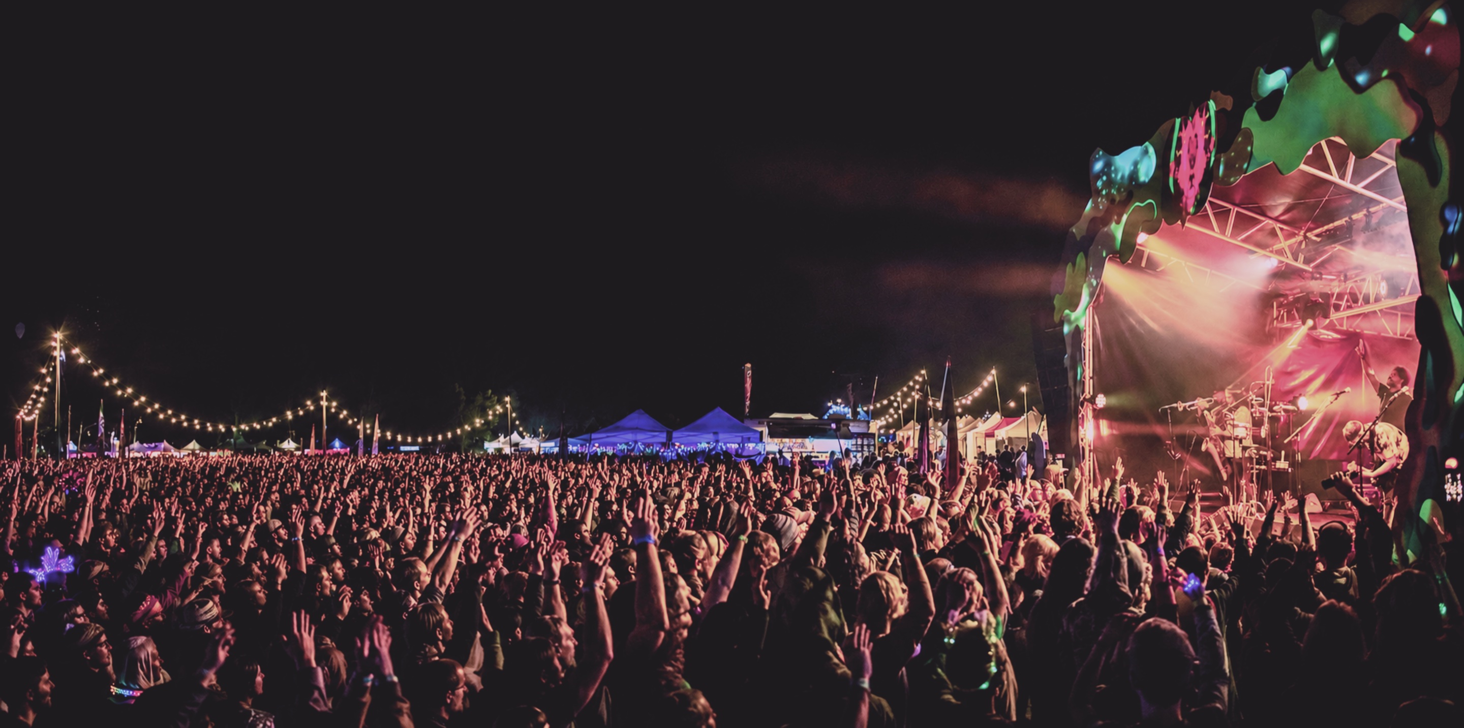 Festival crowd at night before a glowing mainstage